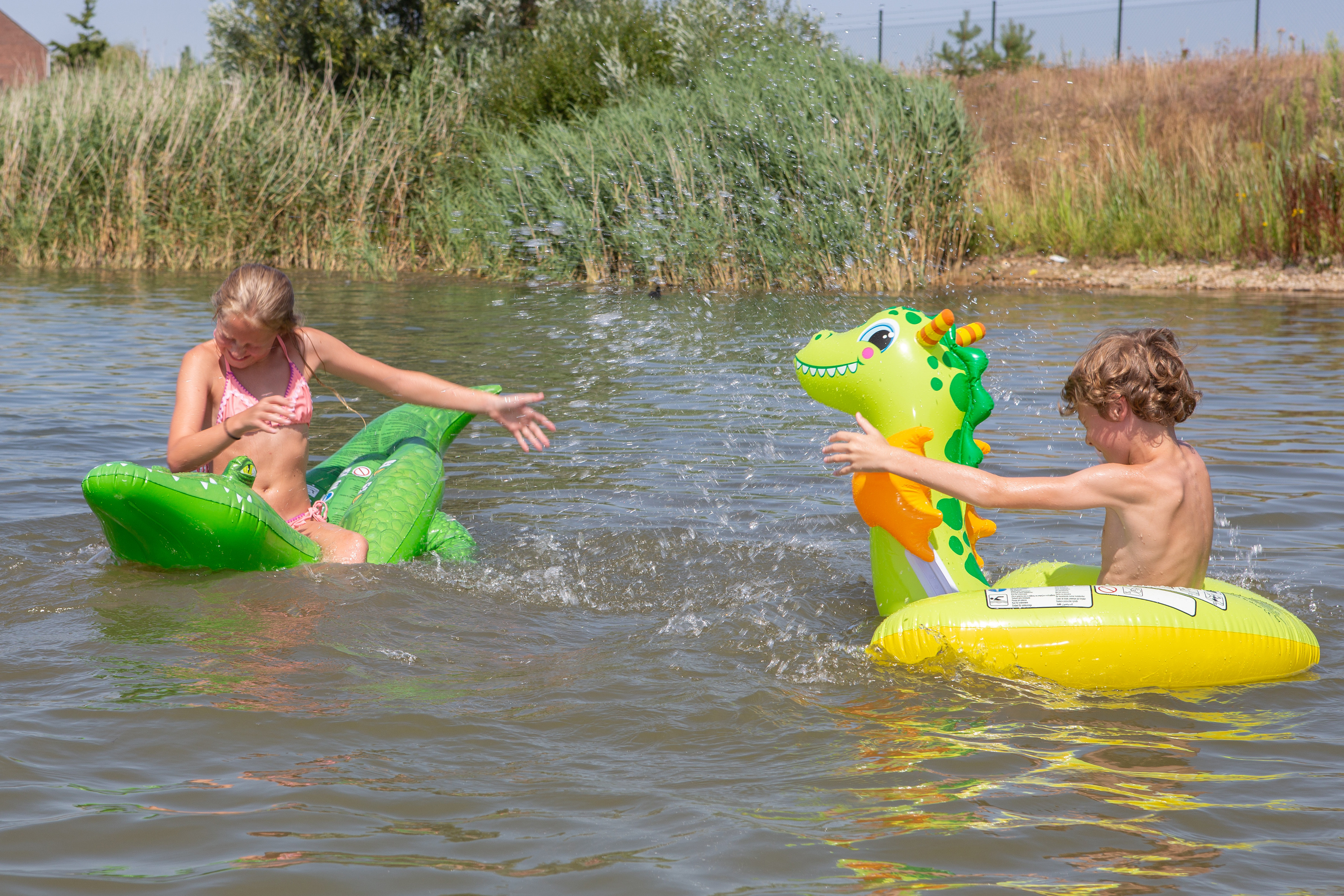 Kinderen spelen met opblaasdieren in het water bij BillyBird Park Drakenrijk op een zonnige dag.